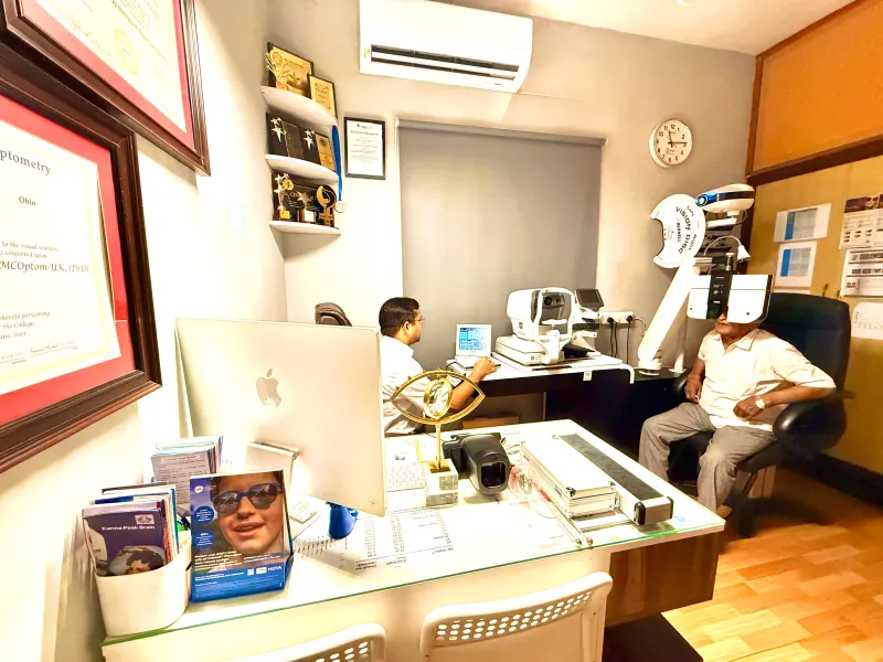 Caring Vision Therapy Ashok Nagar Chennai - Doctor in consultation room with patient, auto-refractor and professional credentials on wall
