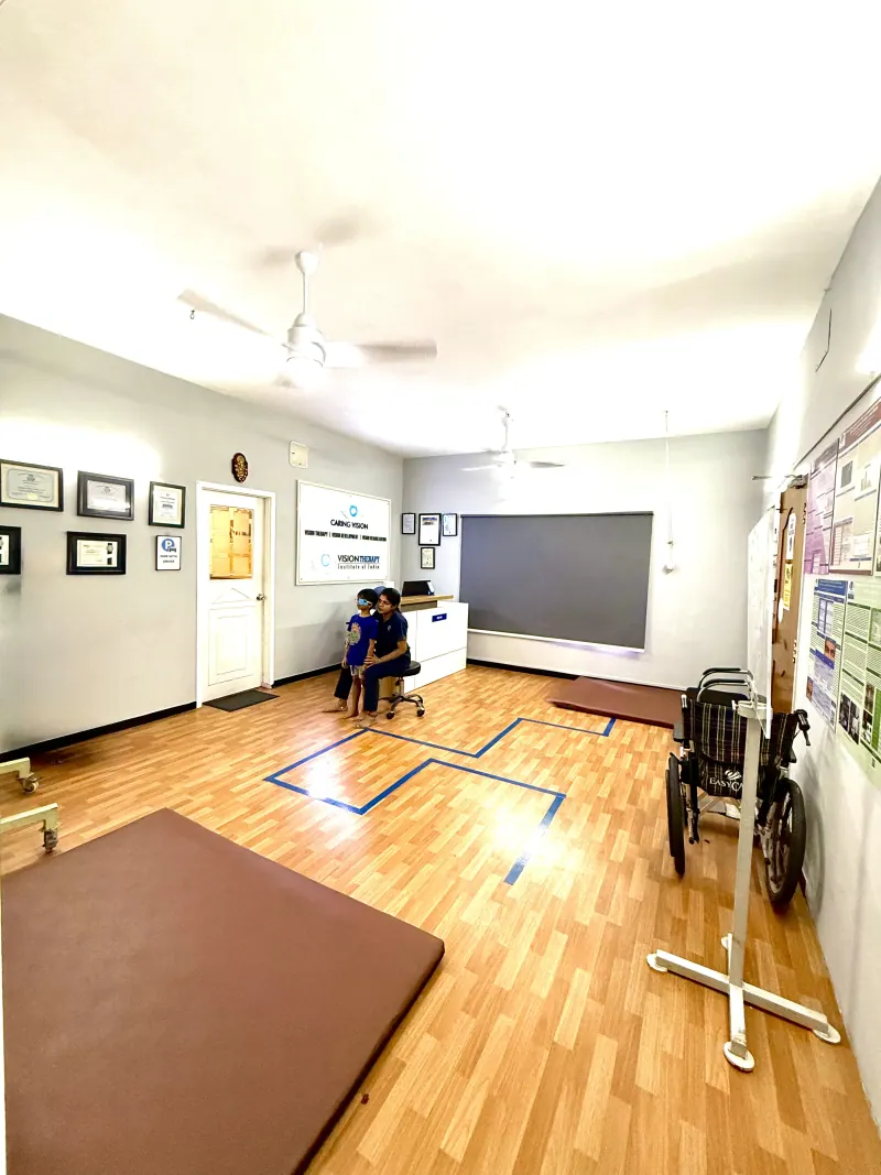 Caring Vision Therapy Ashok Nagar Chennai - Neuro-rehabilitation therapy room with blue floor markers, therapy mat, wheelchair access and interactive screen