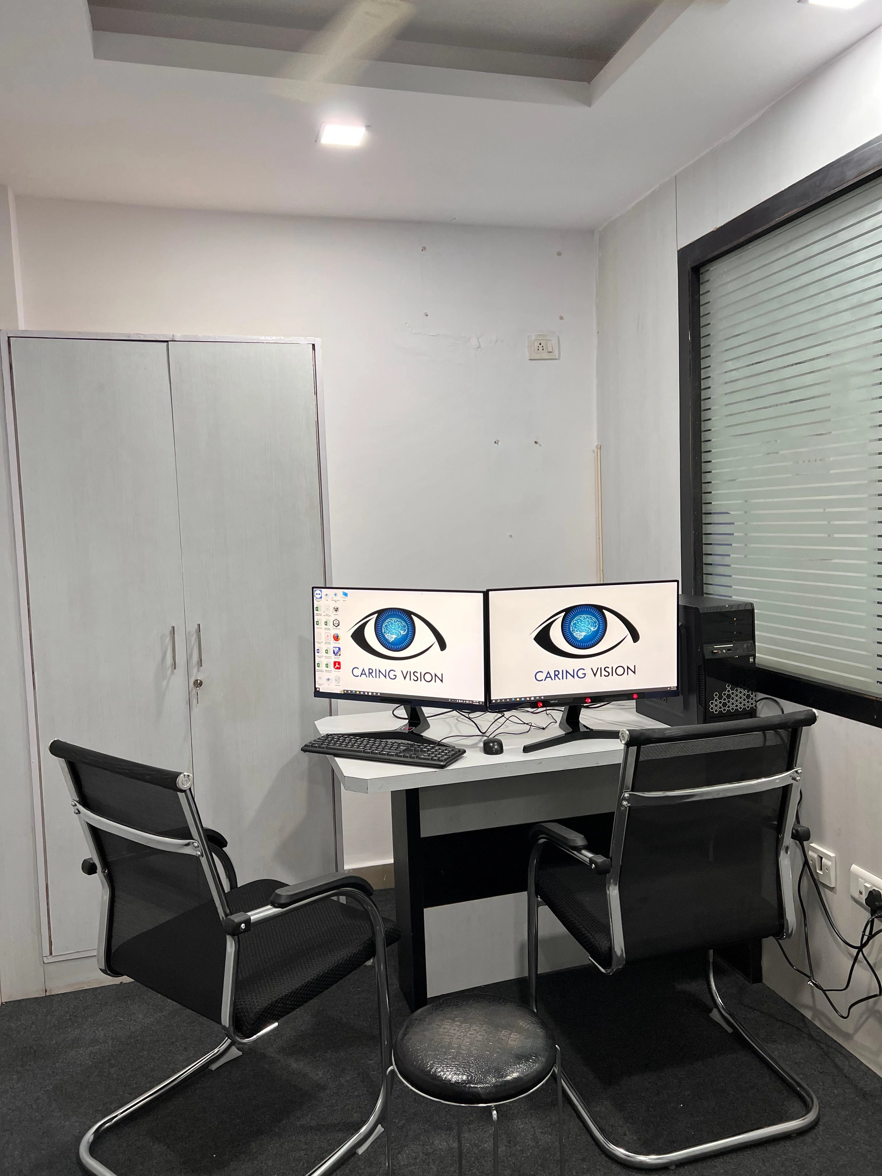 Caring Vision Therapy Hyderabad – Consultation room with dual Caring Vision branded monitors and patient seating