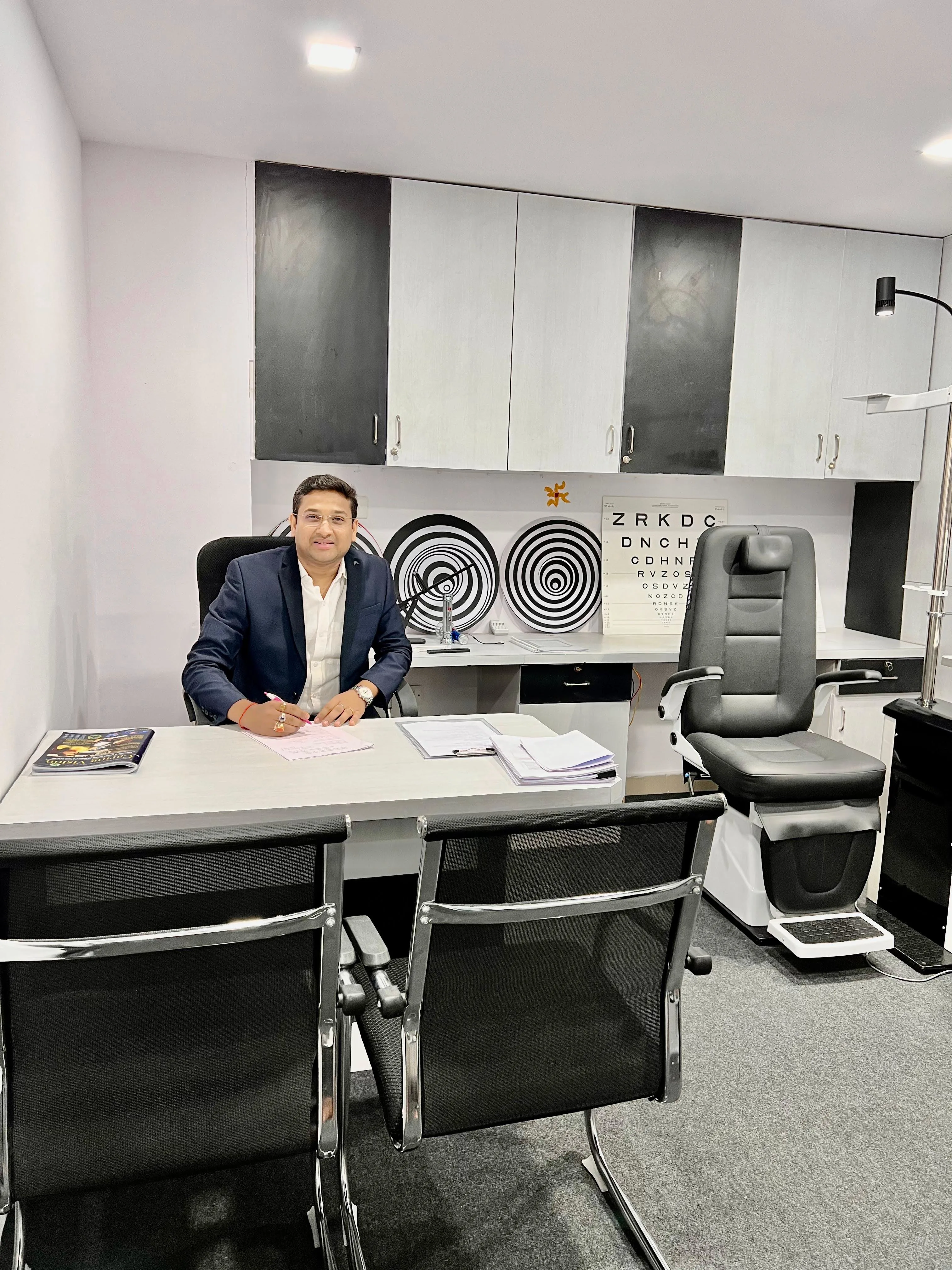 Caring Vision Therapy Hyderabad – Doctor at consultation desk with Snellen eye chart and patient examination chair