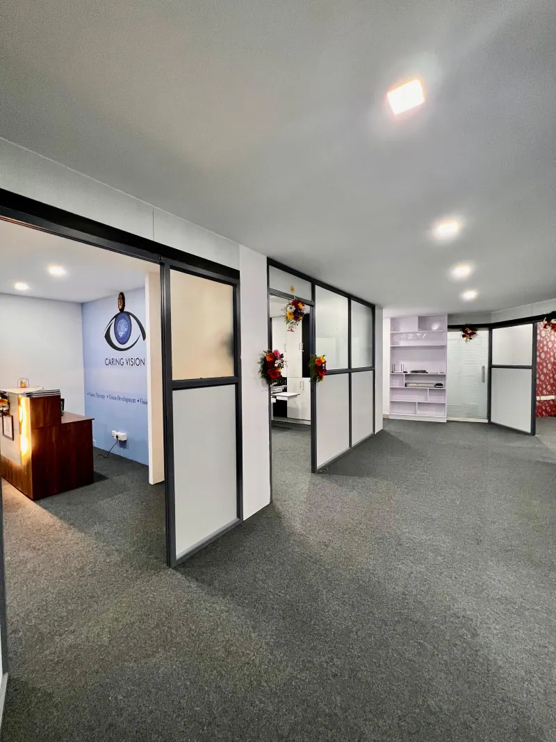 Caring Vision Therapy Hyderabad - Overview of glass-partitioned therapy rooms with clinic branding wall